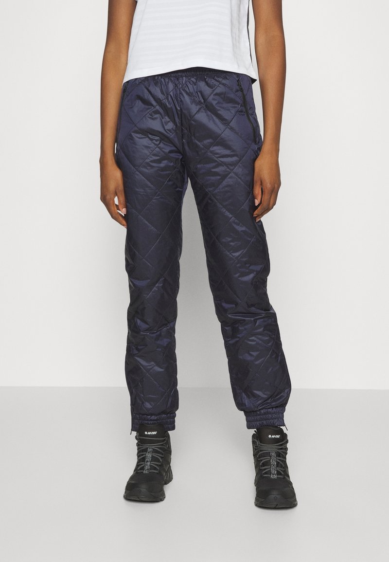 Marina blå quiltade byxor tillverkade av glänsande tyg med elastisk midja och fickor med dragkedja; avsmalnande ärmslut med elastik för en snug passform.