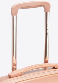 Mango retráctil de una maleta rígida beige con una asa superior para llevar y la marca "WITTCHEN" en la barra metálica.