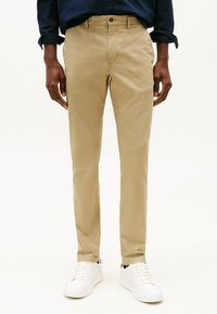 Beige katoenen chino broeken met een rechte pasvorm, voorzakken en een knoopsluiting, gecombineerd met witte sneakers. Soepele textuur.