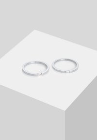 Sæt af sølvringe med et minimalistisk design. Hver ring har en lille, klar ædelsten som accent og en glat, poleret overflade.