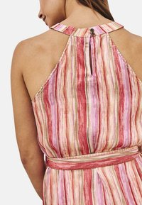 Vestido de cuello halter con rayas verticales multicolores en tonos rosa y beige. Presenta un agujero en la espalda y un cinturón a juego. Textura sedosa.