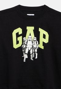Μαύρο φούτερ με γραφική απεικόνιση τριών stormtroopers και έντονο κίτρινο κείμενο "GAP" πάνω τους.