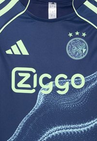 Tamsiai mėlynas sportinis marškinėliai, pagaminti iš kvėpuojančios medžiagos, su šviesiai žaliais akcentais, Adidas logotipu, zigzago grafika ir klubo emblema su trimis žvaigždėmis.