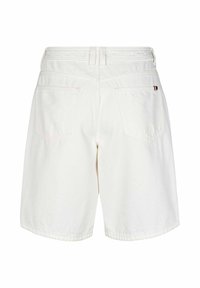 Shorts en jean blanc vus de dos, avec deux poches arrière, passants pour ceinture et une petite étiquette en tissu avec logo sur la poche droite.