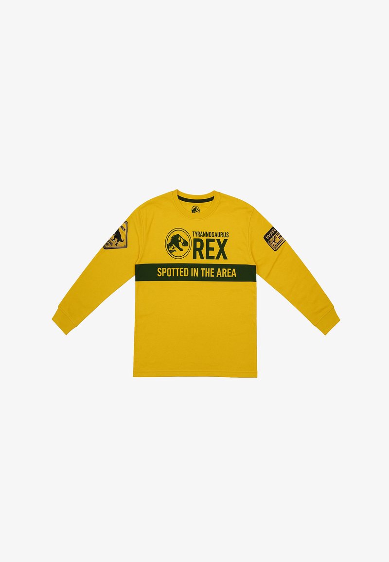 Camicetta a maniche lunghe gialla con "Tyrannosaurus Rex" in testo nero, banda verde a contrasto con il testo "SPOTTED IN THE AREA", e toppe grafiche sulle maniche.
