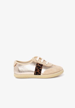 Zapatilla beige con parte superior metálica brillante, detalles en ante y una banda con estampado de leopardo. Incluye cordones blancos y suela de goma texturizada.
