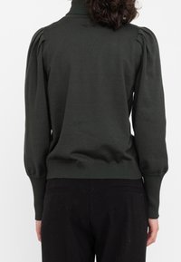 Dunkelgrüner Pullover mit hohem Kragen, gepufften Schultern und gerippten Bündchen und Saum. Die Textur wirkt glatt und leicht tailliert.