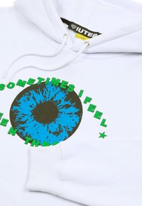 Felpa bianca in cotone con una grande grafica di occhio blu e marrone accompagnata da testo verde che recita "A VOLTE MI SENTO VISTO ATTRAVERSO," e cordino.