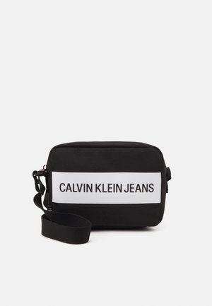 Schwarze Schultertasche mit rechteckiger Form, hergestellt aus strukturiertem Material. Verfügt über ein weißes, horizontales Logo-Panel mit der Aufschrift "CALVIN KLEIN JEANS."