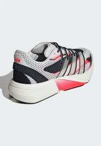 Lightweight running shoe featuring a mesh upper in white with black and red accents, a thick white midsole, and a black rubber outsole.