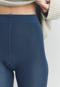 Navy modré žebrové legíny s vysokým pasem, s hladkou texturou a viditelným švem podél švů.