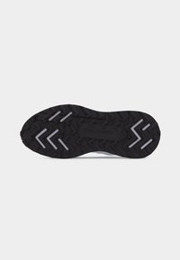 Semelle de chaussure en caoutchouc noir avec bande de roulement texturée, accents angulaires blancs et logo « Lacoste » au centre.