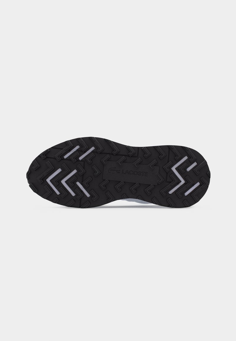 Schwarze Gummisohlen mit strukturiertem Profil, weißen eckigen Akzenten und dem "Lacoste"-Logo in der Mitte.