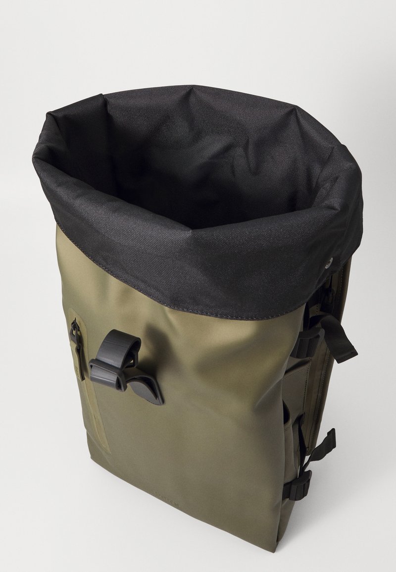 Sac à dos roulé vert olive avec un dessus imperméable noir, boucles latérales réglables et une poche zippée à l'avant. Matériau durable, forme rectangulaire.