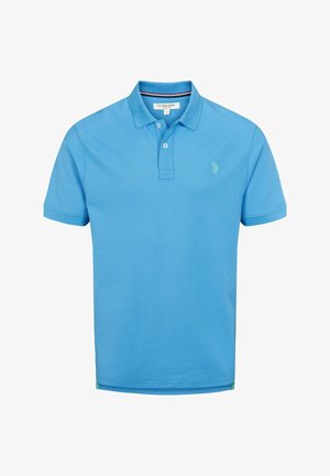 Gaiši zils kokvilnas polo krekls ar divām pogām, ribinātu apkakli un mazu zaļu logo kreisajā krūtī.