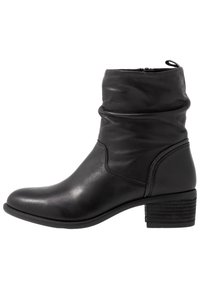 Bottines en cuir noir avec un design décontracté, bout rond et un talon empilé avec des détails texturés. Fermeture éclair sur le côté pour un enfilage facile.