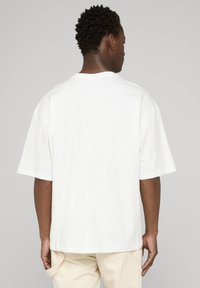 Hvid bomulds t-shirt med en afslappet pasform, korte ærmer og rund halsudskæring, med et enkelt design uden synlige logoer eller mønstre.