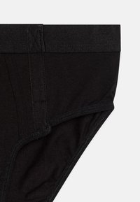 Slip in cotone nero con una larga fascia elastica. Presenta una superficie liscia e bordi cuciti, mostrando un design classico per slip.
