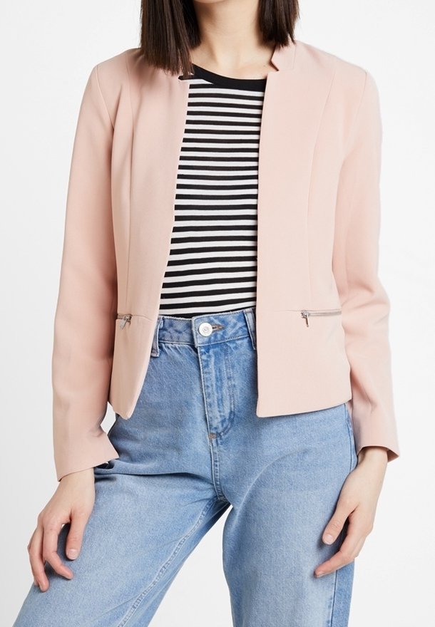 Ljusrosa blazer med en strukturerad design, långa ärmar och två framfickor med dragkedja, tillsammans med en svart-vit randig skjorta och jeans.