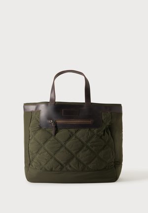 Sac cabas matelassé vert avec des poignées en cuir marron et une poche avant zippée.