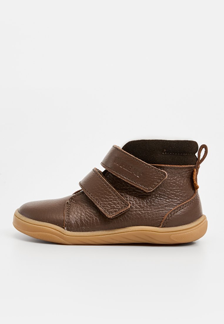 Brauner Lederschuh mit zwei verstellbaren Klettverschlussriemen, texturiertem Finish, runder Zehenform und einer Gummisohle mit einem hellbraunen Akzent.