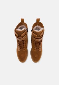 Botas de tobillo de ante beige con cordones, parte superior texturizada, suave forro gris y dobles cremalleras. Presenta lengüetas en el puño para facilitar su uso.