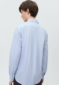 Ljusblå randig långärmad skjorta i bomull, med en klassisk krage, knäppmanschetter och en böjd nederkant.