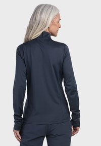 Marineblaue, langärmlige Sportoberteile mit hohem Kragen, aus glattem, leichtem Material, ausgestattet mit nahtlosen Schultern und Daumenlöchern an den Bündchen.