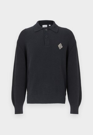 Pullover navy a costine con colletto a punta, tre bottoni e logo a diamante sul petto. Maniche lunghe, leggermente a sbuffo.