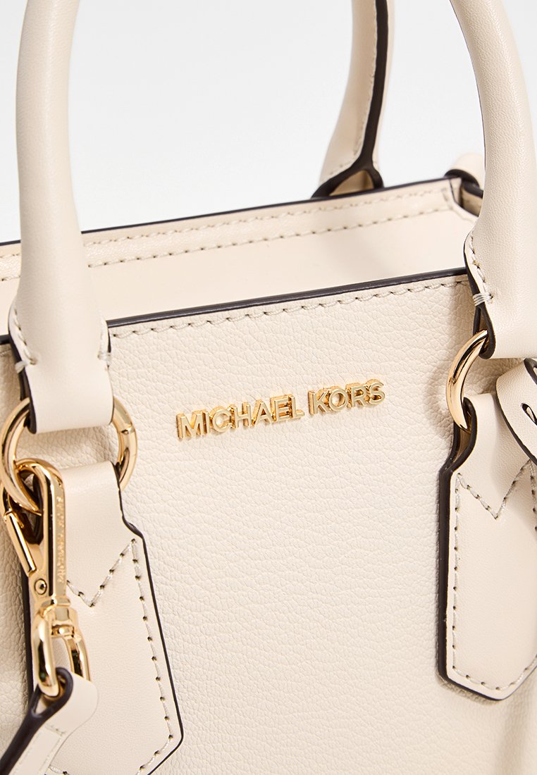 Lederhandtasche in Creme mit goldfarbigen Beschlägen, verfügt über zwei oben angebrachte Griffe, Logodetails und kontrastierende dunkle Kanten. Strukturiertes Finish.