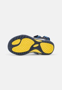 Sola de sandália desportiva com uma base de borracha preta texturizada e um padrão de tração amarelo. Correias ajustáveis com um design tecido em azul e preto.