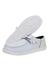 Zapato slip-on de tela blanca con un acabado texturizado, forro azul marino en contraste, cordones grises y una suela de goma con un patrón que presenta un diseño de estrellas.