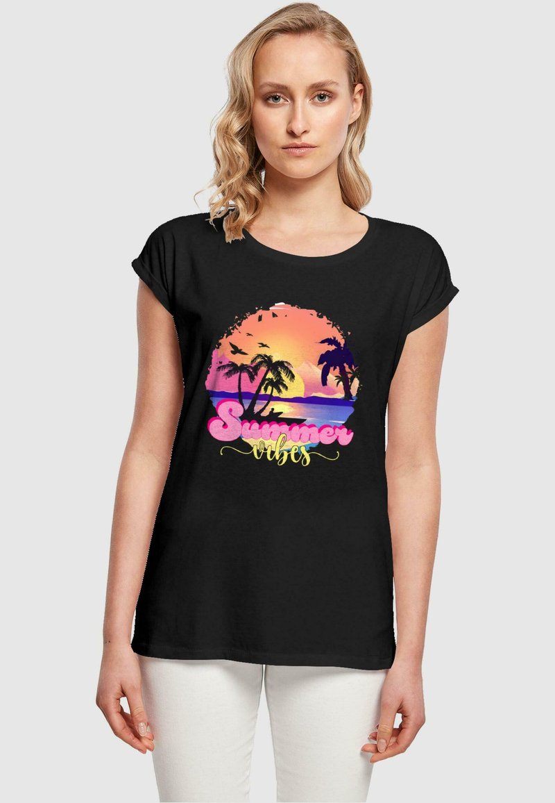 Svart t-skjorte med kort erm som har et fargerikt solnedgangsdesign med palmer og teksten "Summer Vibes" i rosa og gul.