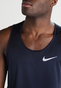 Débardeur bleu marine en matière lisse et légère, doté d'un col rond et d'un petit logo Nike blanc sur la partie gauche de la poitrine.