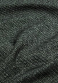 Texturovaná tkanina v tmavě zelené barvě s jemným vzorem. Materiál vypadá tkaný a má měkký, mírně vystouplý povrch.