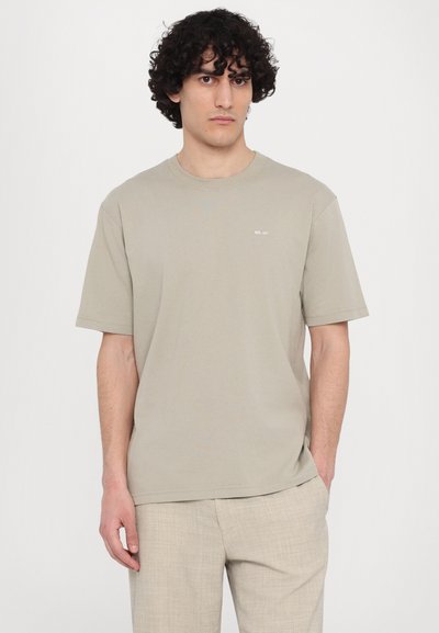 Korte mouwen, lichtbeige katoenen t-shirt met een ronde hals en een klein wit logo op de linkerborst. Glad textuur, comfortabele pasvorm.