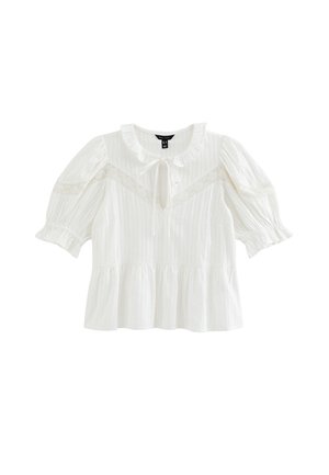 Blusa blanca de manga corta con cuello fruncido, detalle de encaje en el pecho y las mangas, escote con abertura en forma de ojo de cerradura con lazo, y bajo estilo peplum.