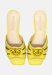 Infradito gialli con design a ritaglio, punta quadrata e un prominente dettaglio del logo giallo sulla parte anteriore. Materiale in faux leather liscio.