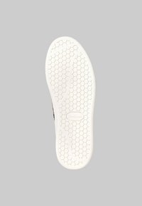Suela de zapato blanca con patrón hexagonal y líneas curvas, que presenta el nombre de la marca "Desigual" grabado en el centro.