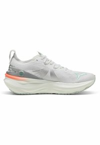 Zapatilla de running blanca con una parte superior texturizada y transpirable, acentos plateados y una suela gruesa y acolchada que presenta detalles en color coral y menta.