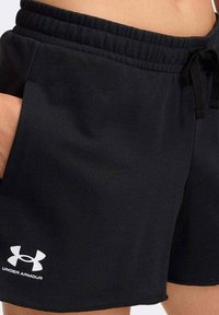 Shorts deportivos negros hechos de tela suave, con una cintura elástica con cordón y bolsillos laterales. Logo de Under Armour en blanco.