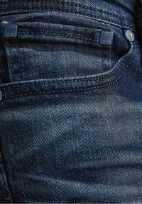 Mörkblå denimjeans med en slät textur, med en framficka, metalldetaljer och subtila sömnadsdetaljer. Varumärkesetikett synlig.