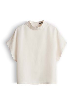 Crèmekleurige blouse met korte mouwen, een hoge ronde halslijn en een losse pasvorm, plat uitgestald op een witte achtergrond.