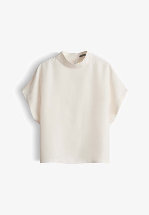 Crèmekleurige blouse met korte mouwen, een hoge ronde halslijn en een losse pasvorm, plat uitgestald op een witte achtergrond.