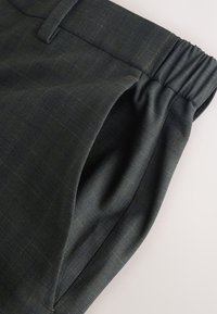 Dark gray checkered pants with an elastic waistband and side pocket shown on a light background.