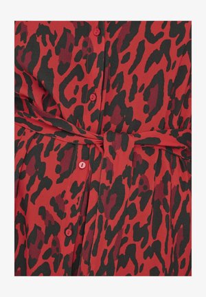 Rdeča in črna obleka z živalskim potiskom, ki vključuje gumbe, pas s vezavo in gladko teksturo tkanine. Oblikovanje vključuje silhueto s pasom.