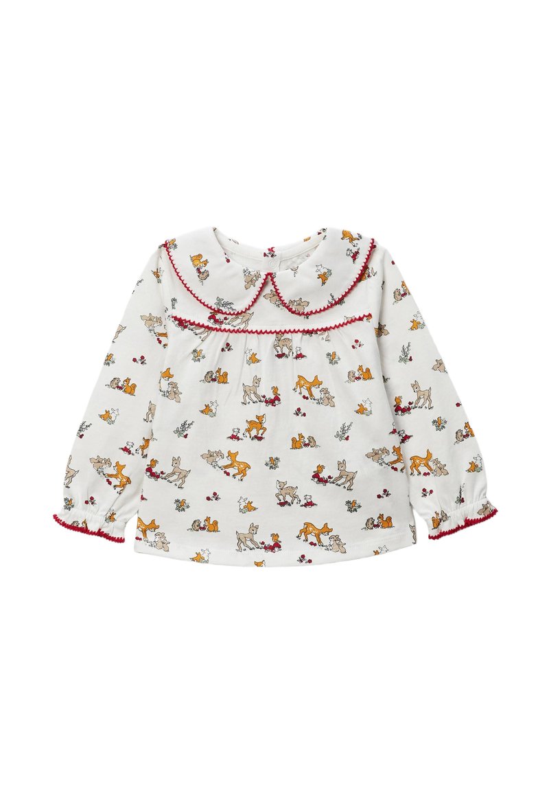 Blouse blanche à manches longues avec un col arrondi, une bordure rouge et un imprimé animalier répétitif mettant en scène des cerfs et de petits animaux. Tissu doux.
