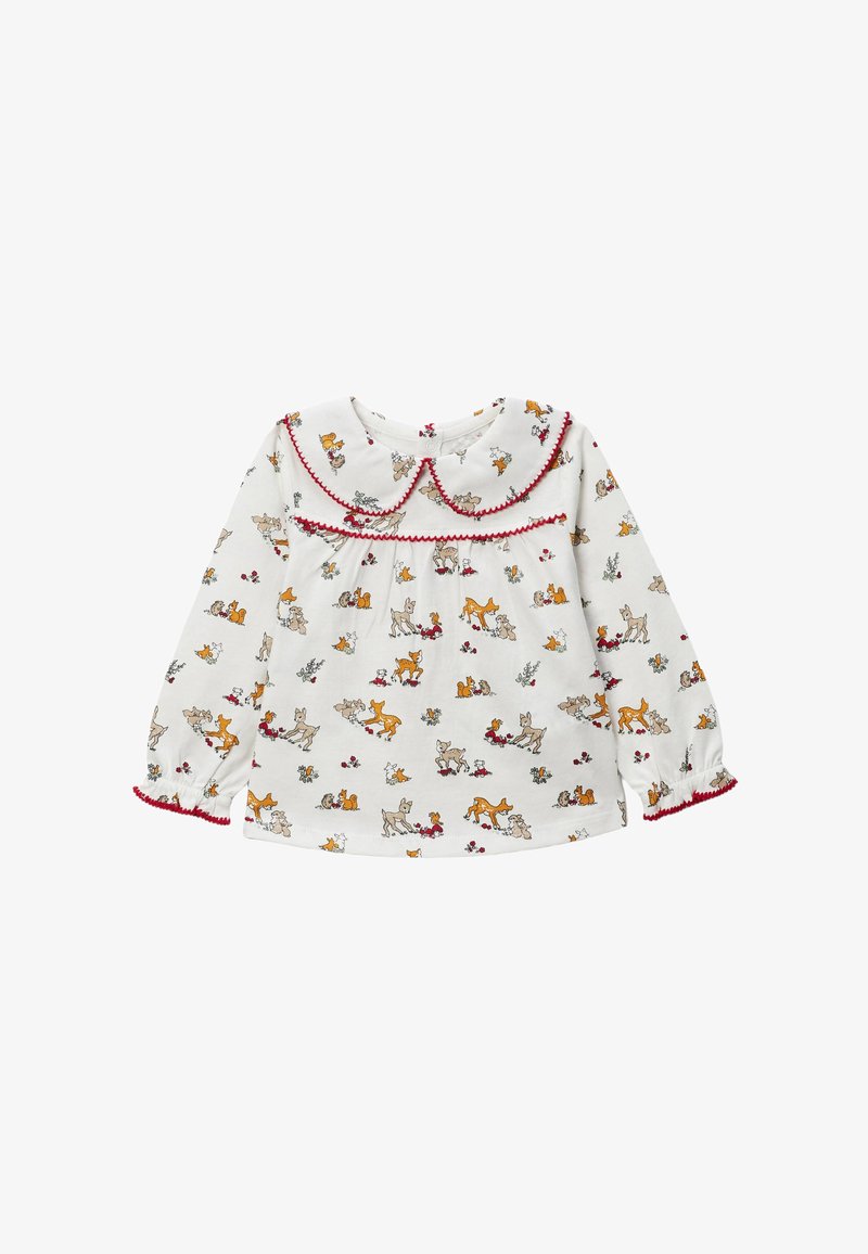 Blouse blanche à manches longues avec un col arrondi, une bordure rouge et un imprimé animalier répétitif mettant en scène des cerfs et de petits animaux. Tissu doux.