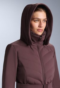 Bordo jakna s kapuljačom i cik-cak prošivom, zatvaračem na patent i mekanim postavom oko ovratnika. Glatki, teksturirani materijal s tijesnim krojem.