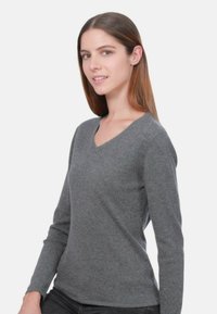 Pull gris à manches longues avec un col en V, fabriqué en maille douce, présentant une coupe ajustée et un style minimaliste.